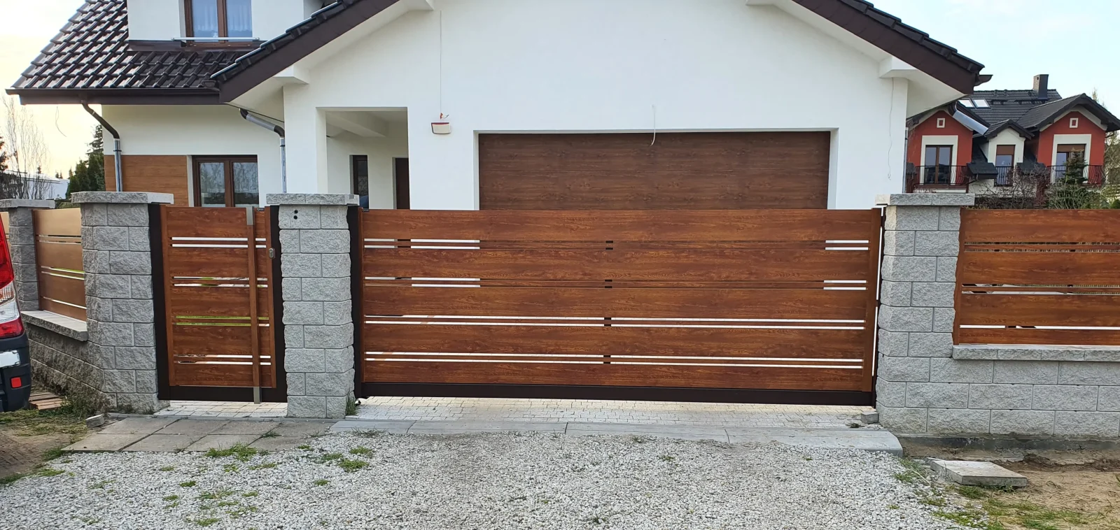 Brama przesuwna aluminiowa w wykończeniu drewnopodobnym z dopasowaną bramą garażową - realizacja Fello