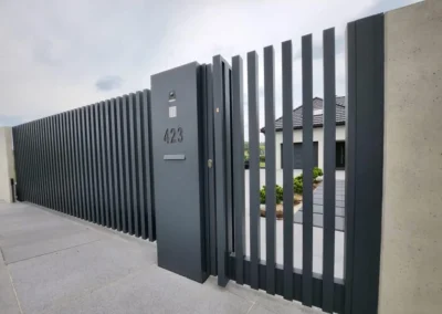 Otwarta brama przesuwna z pionowych lameli i ogrodzenie aluminiowe Fello