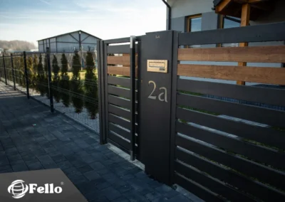 Słupek multimedialny Fello przy ogrodzeniu aluminiowym drewnopodobnym